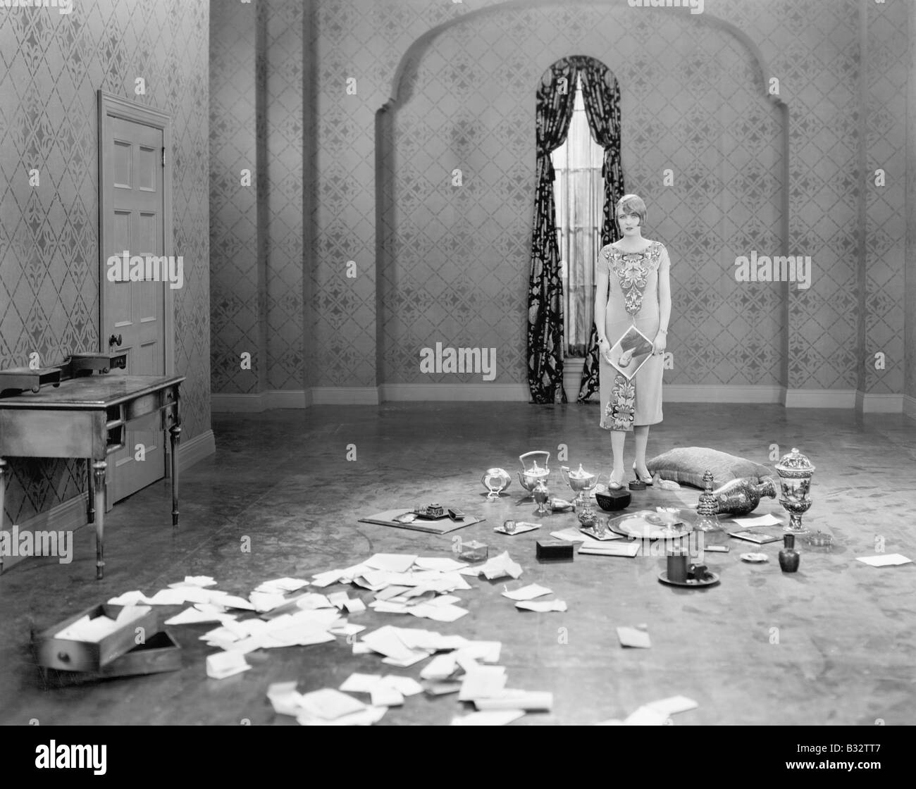 Femme debout dans une salle vide avec des lettres éparpillées Banque D'Images