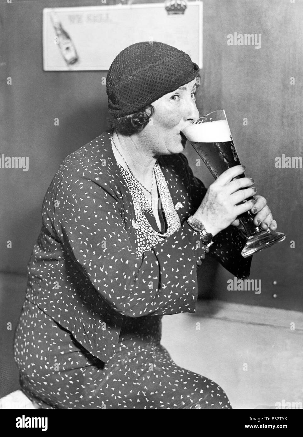 Femme buvant hors d'un grand verre de bière Banque D'Images
