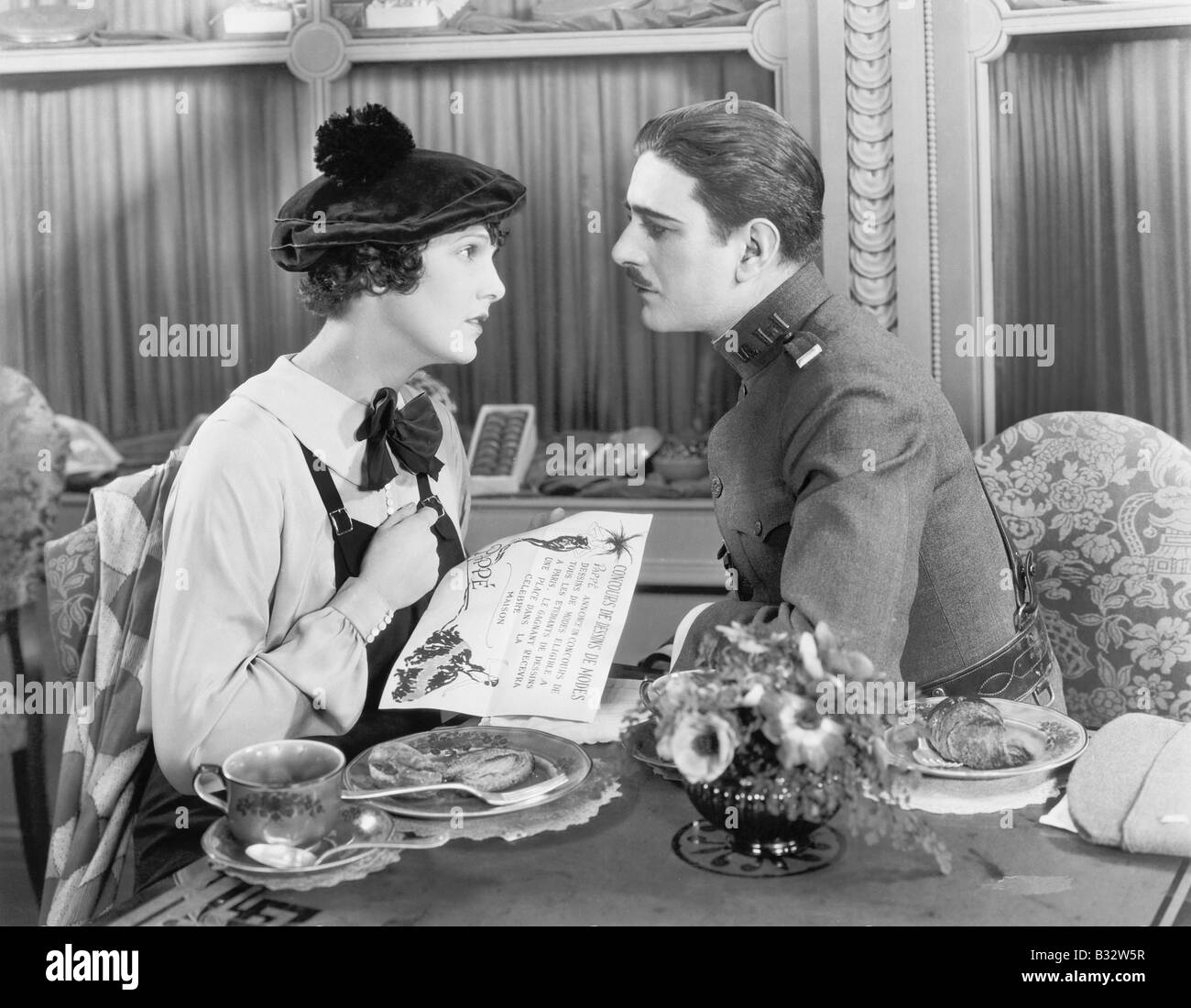 Homme en uniforme et d'une femme assis ensemble à une table et regarder Banque D'Images