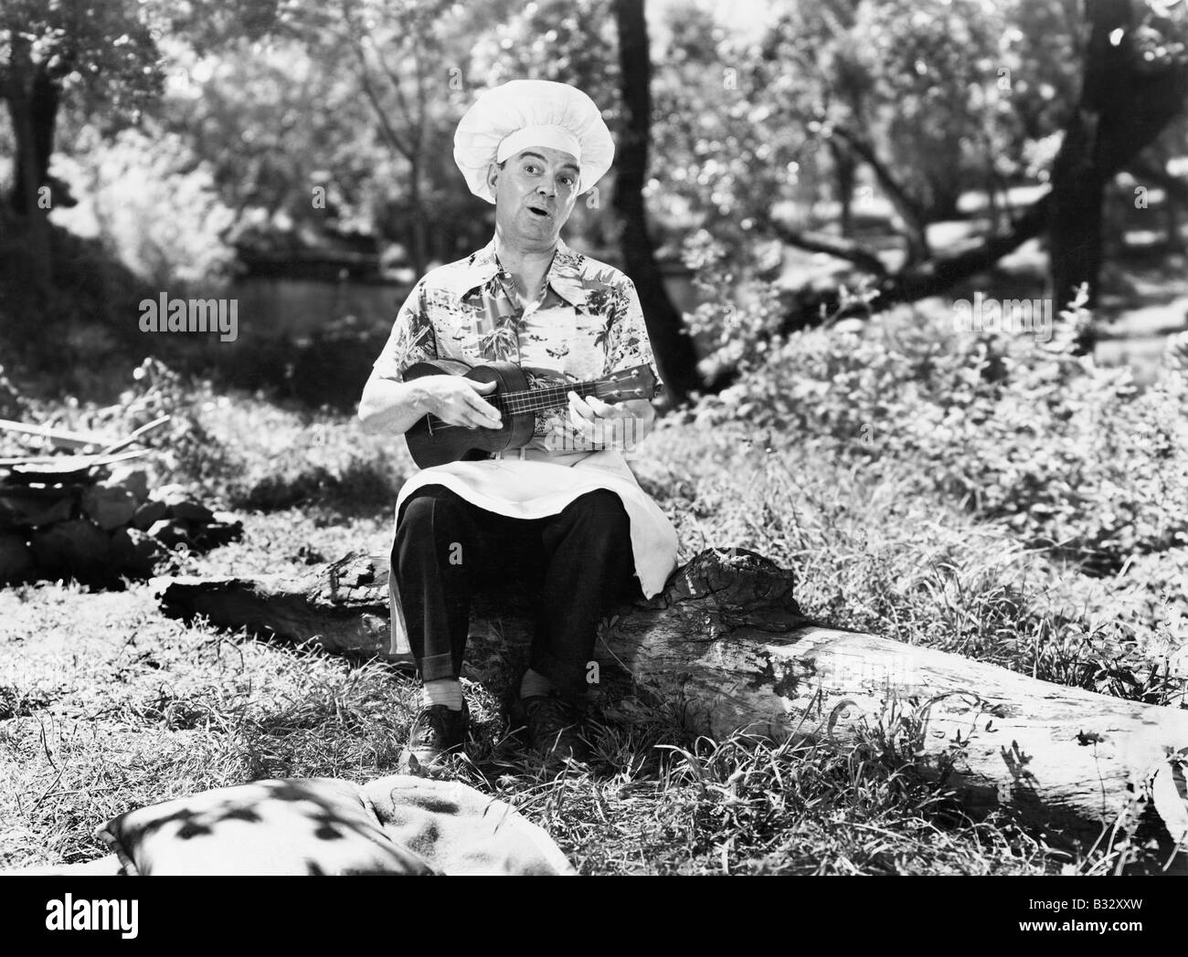 Homme dans un chefs hat assis dehors et jouer le yukalalee Banque D'Images