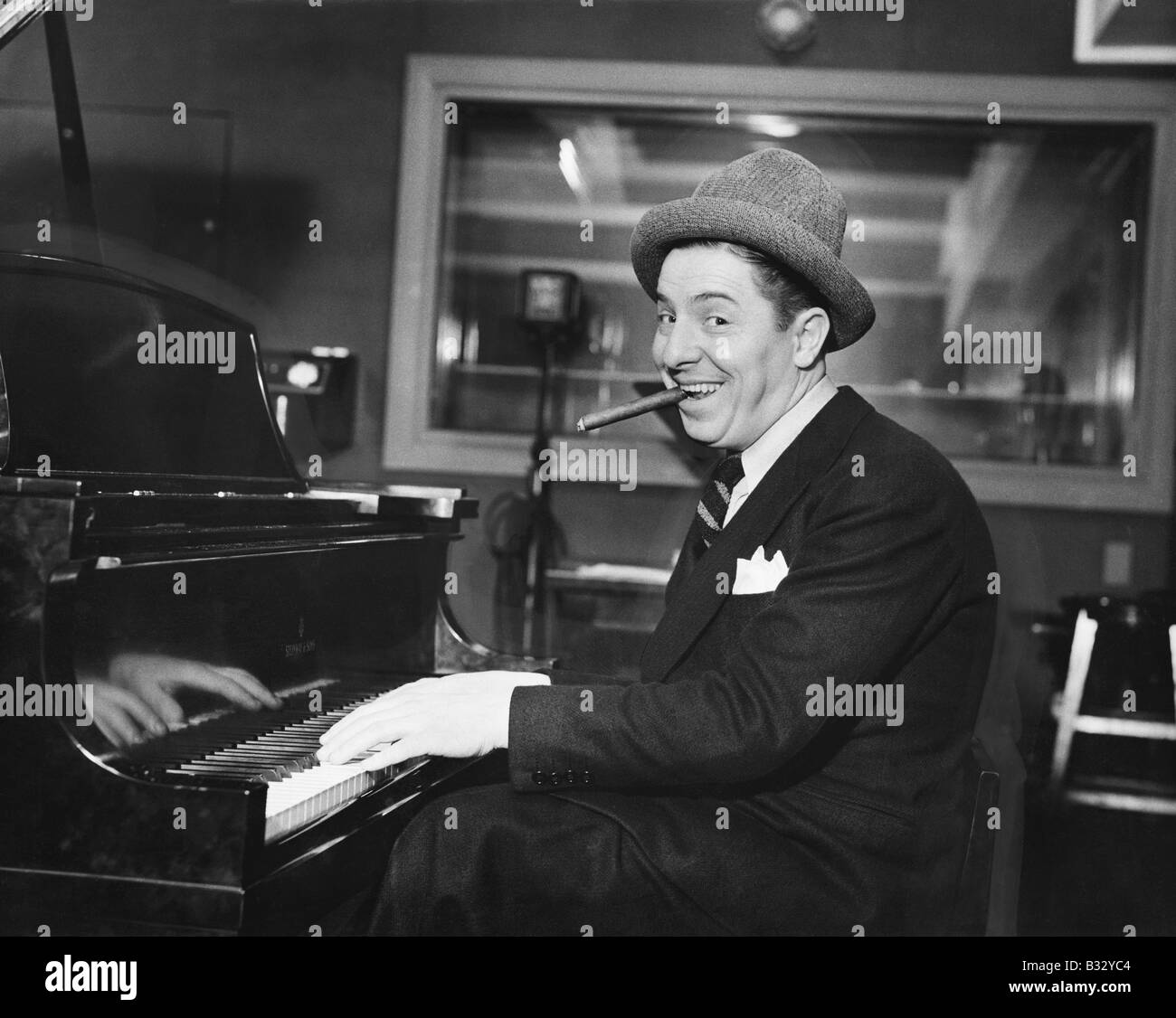 Homme avec un grand sourire et un cigare dans sa bouche jouer du piano Banque D'Images