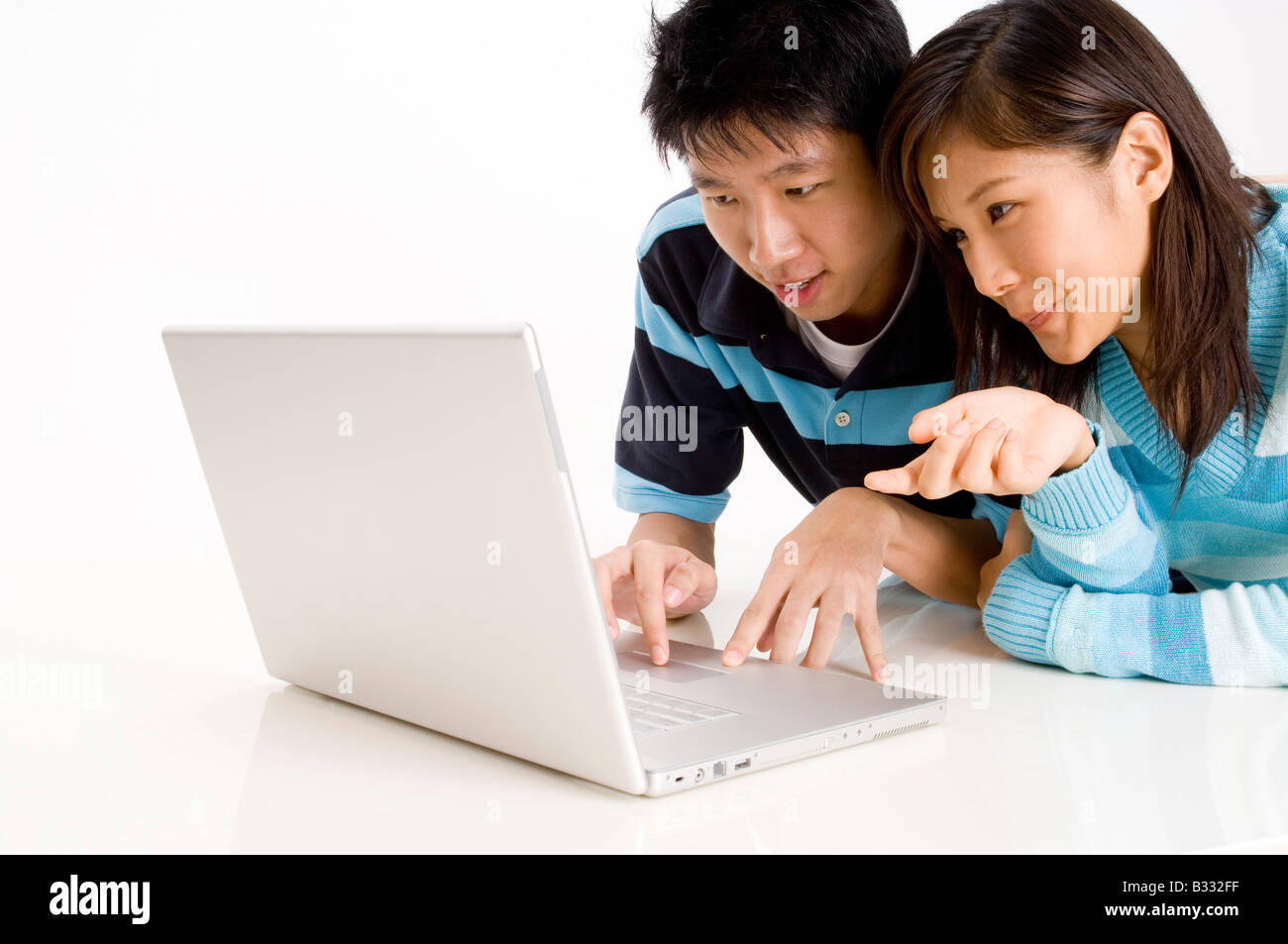 Un jeune couple se trouvant sur le plancher à l'aide d'un ordinateur portable Banque D'Images