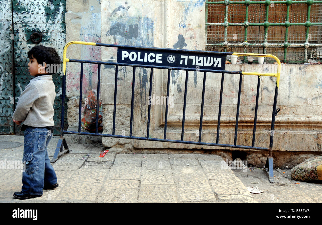 Une scène de rue dans le quartier arabe de la vieille ville de Jérusalem, une barrière de la police israélienne s'assied à côté d'une allée en pierre. Banque D'Images