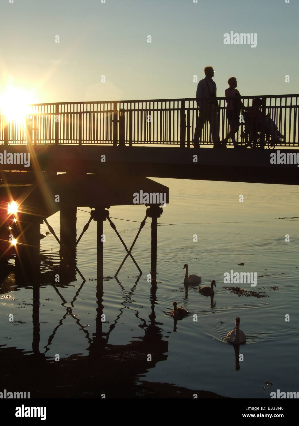 Moody scène de personnes crossing bridge au coucher du soleil Banque D'Images