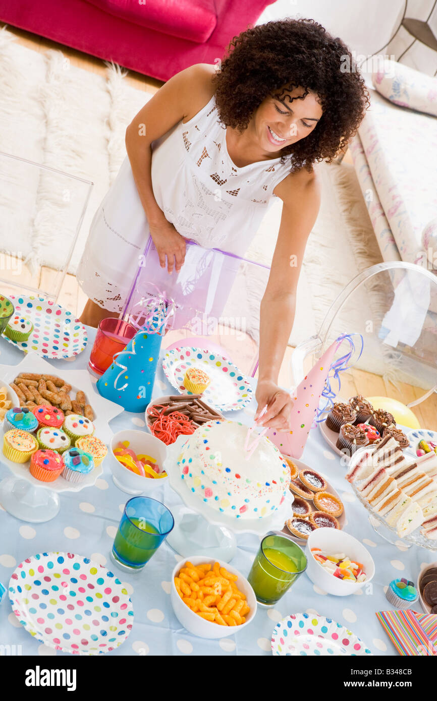 Femme à partie de mettre des bougies dans le gâteau sur la table des aliments smiling Banque D'Images
