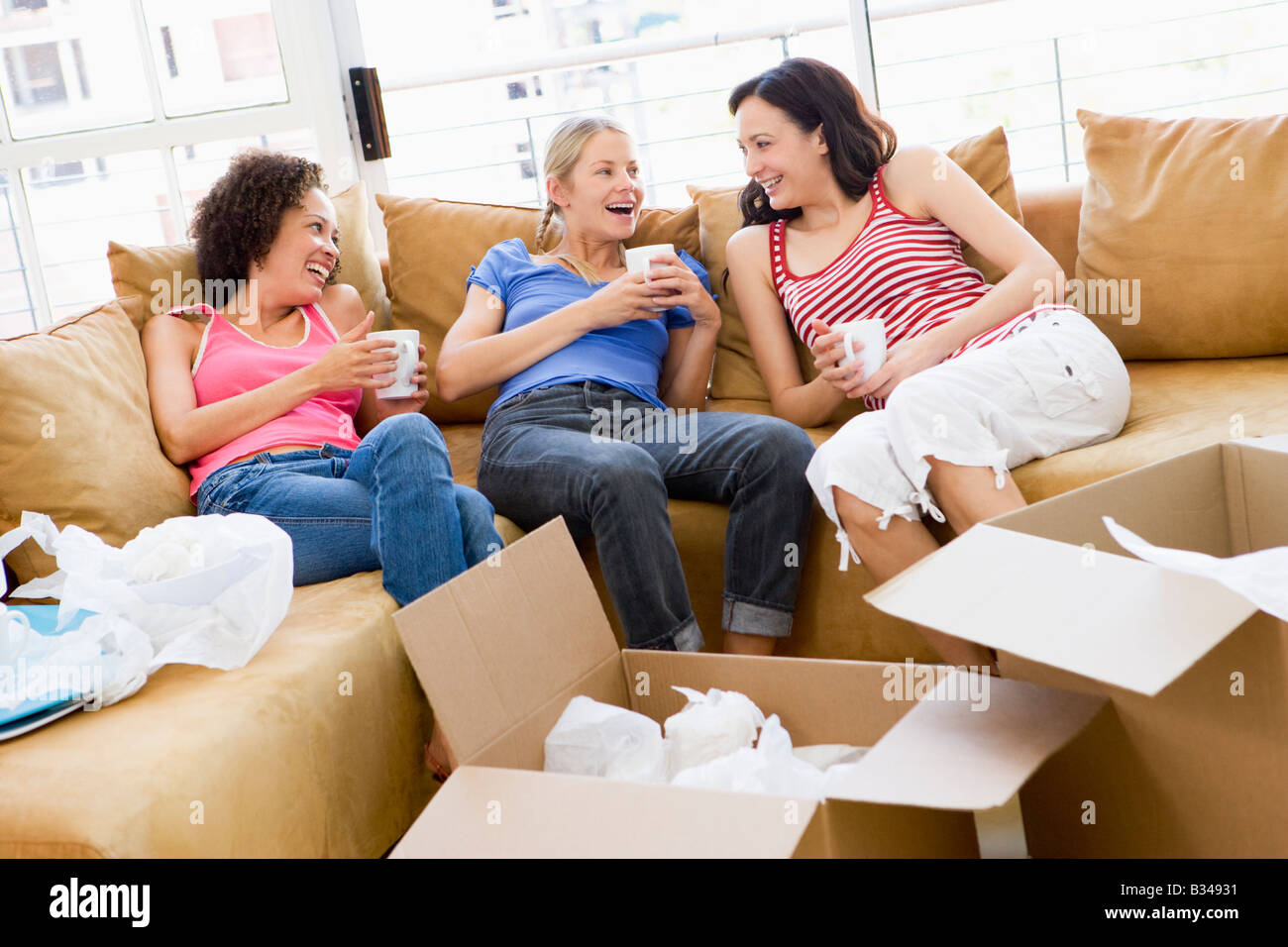 Trois amies se détendre avec du café par des boîtes à new home smiling Banque D'Images