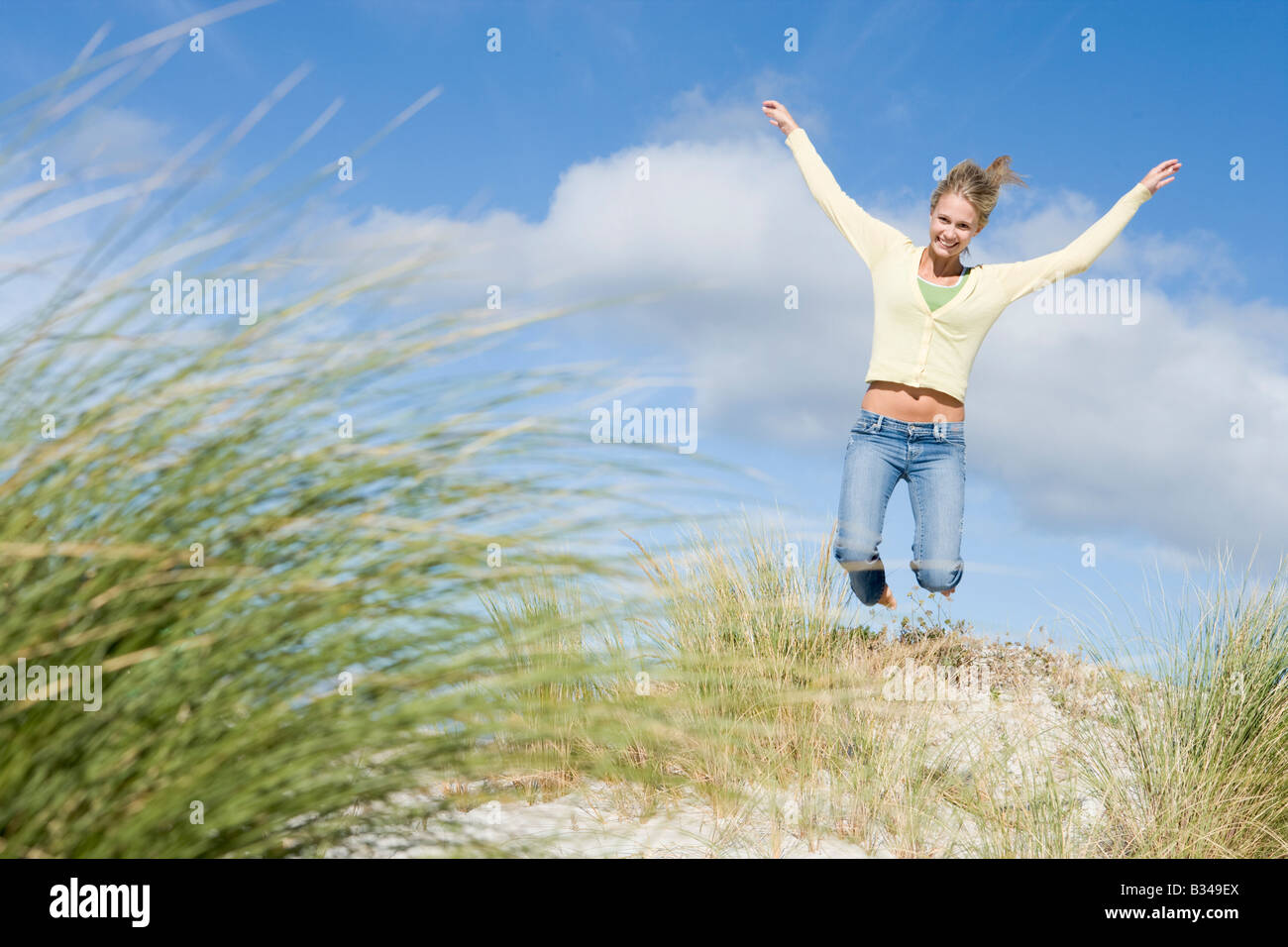 Jeune femme sautant sur une colline de sable Banque D'Images