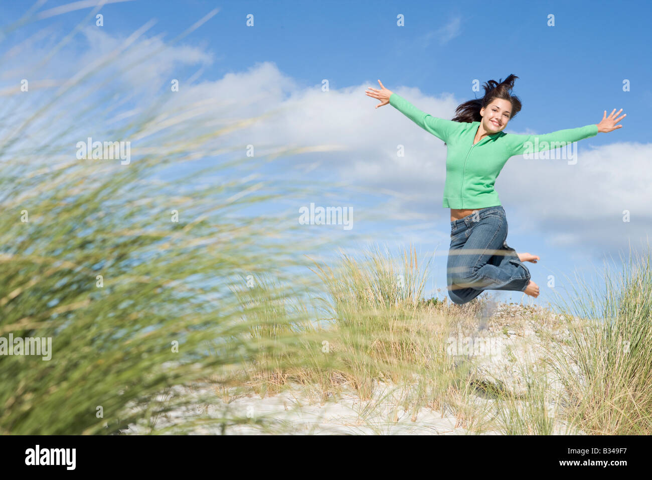 Jeune femme sautant sur une colline de sable Banque D'Images