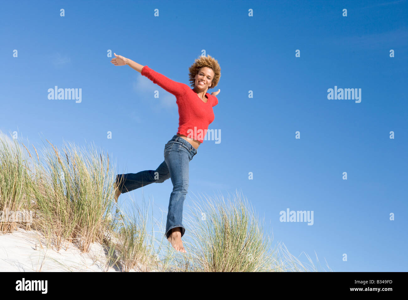 Jeune femme sautant sur une colline de sable Banque D'Images