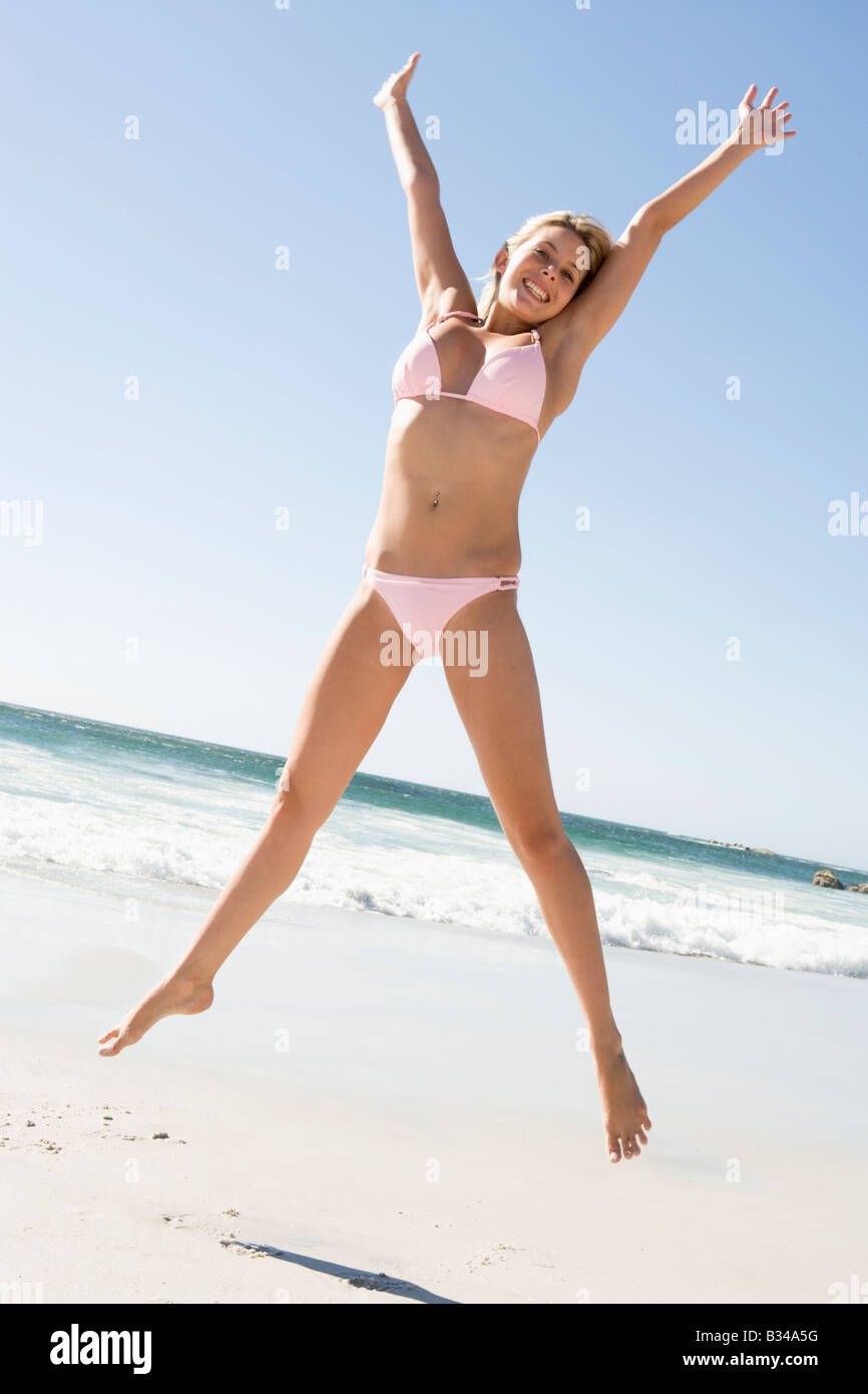 Femme dans un maillot deux pi ces sautant sur une plage Photo
