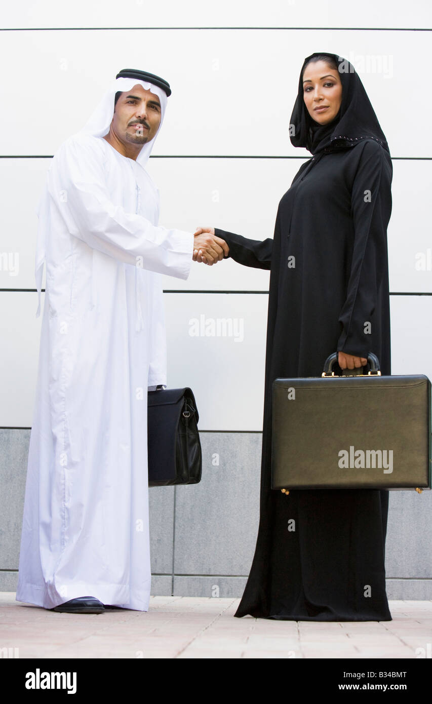 Deux businesspeople standing en plein air avec porte-documents shaking hands Banque D'Images