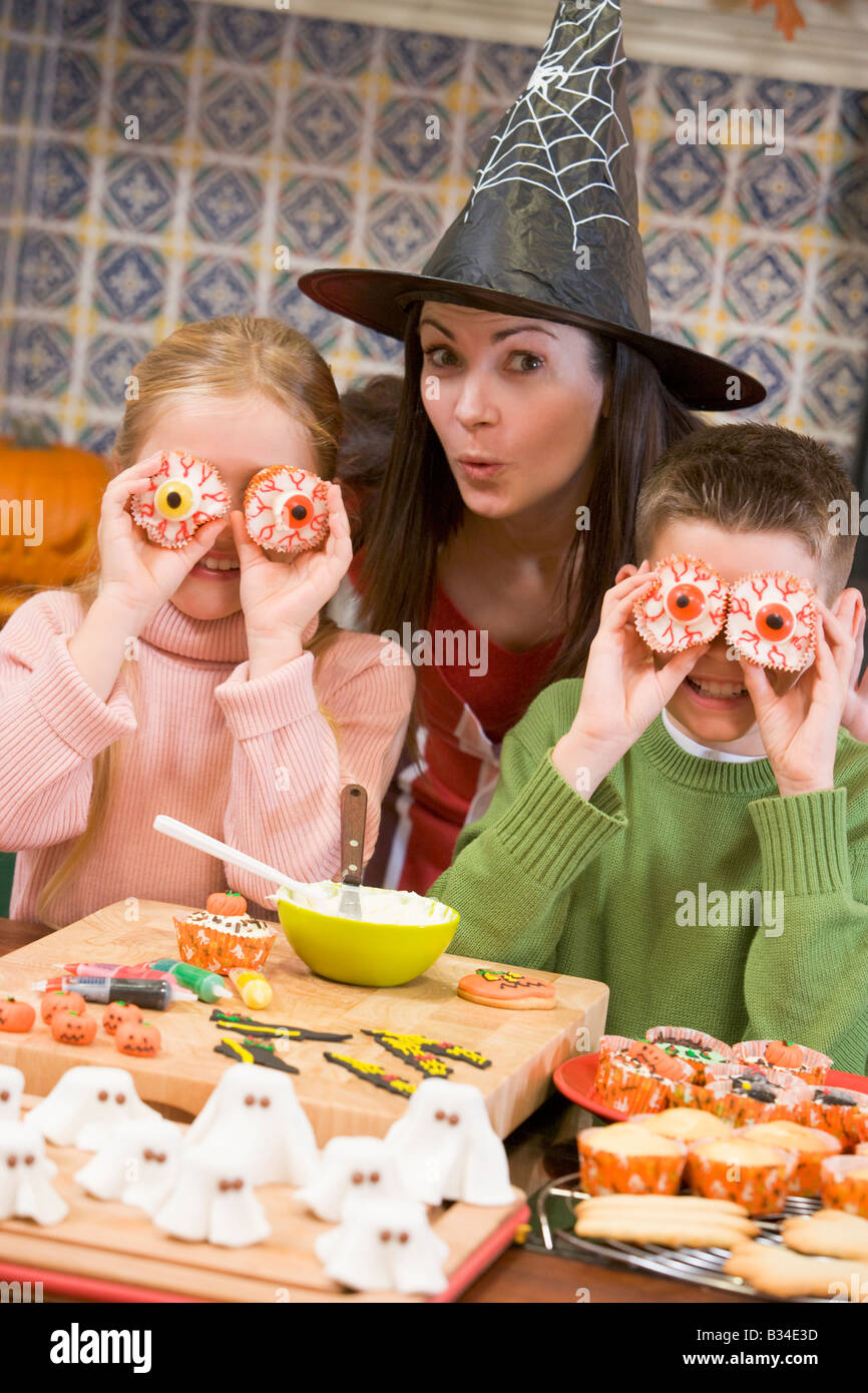 La mère et deux enfants à l'Halloween jouer avec des friandises et souriant Banque D'Images