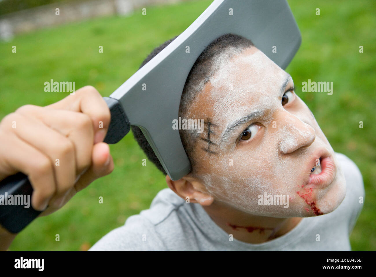 Jeune garçon avec Scary Halloween maquillage et tête de couteau en plastique Banque D'Images