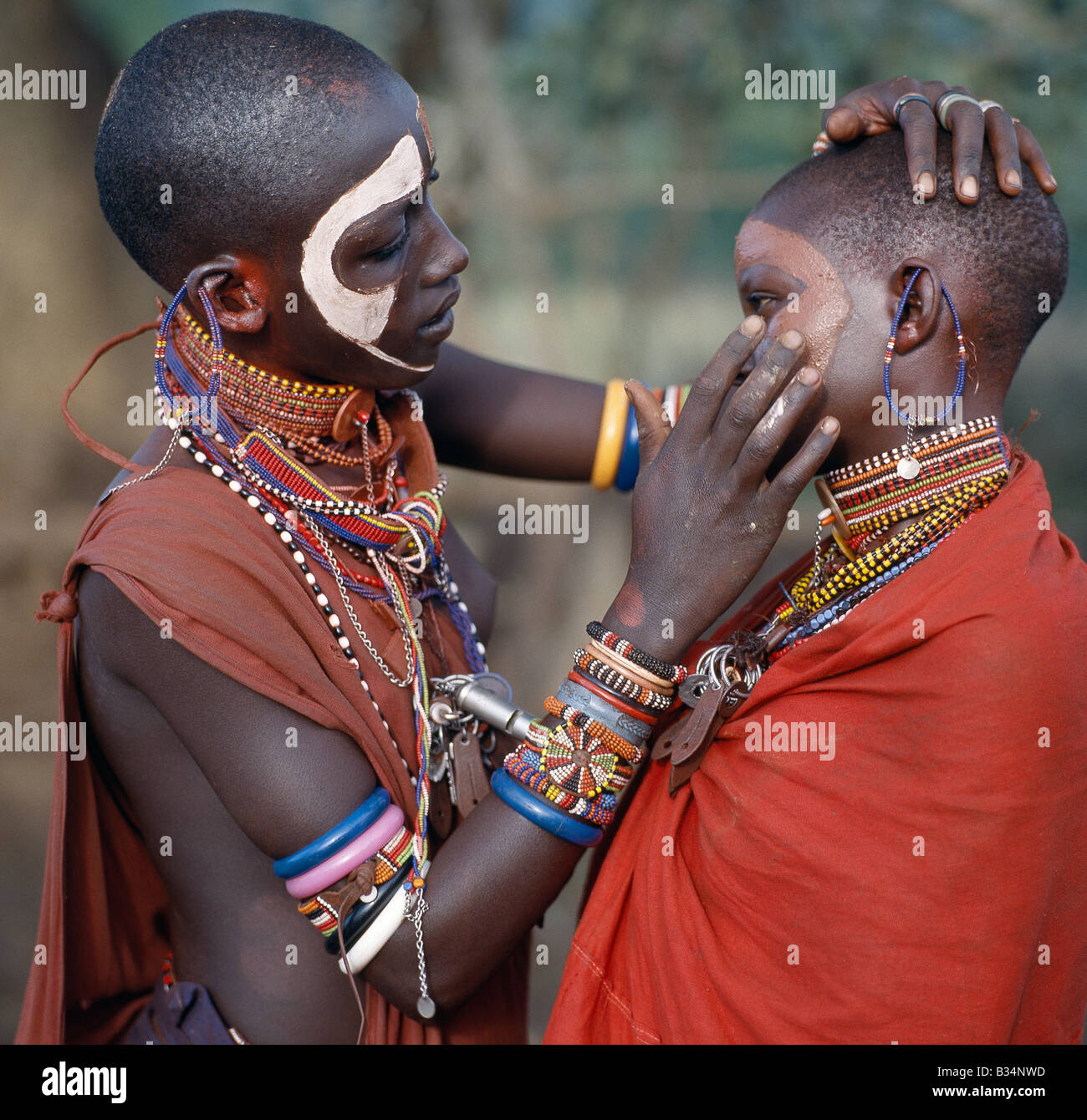 Kenya, Trans-Mara, Lolgorien. Les jeunes filles Maasai décorer leurs visages à l'ocre et d'argile dans la préparation d'une danse. Banque D'Images