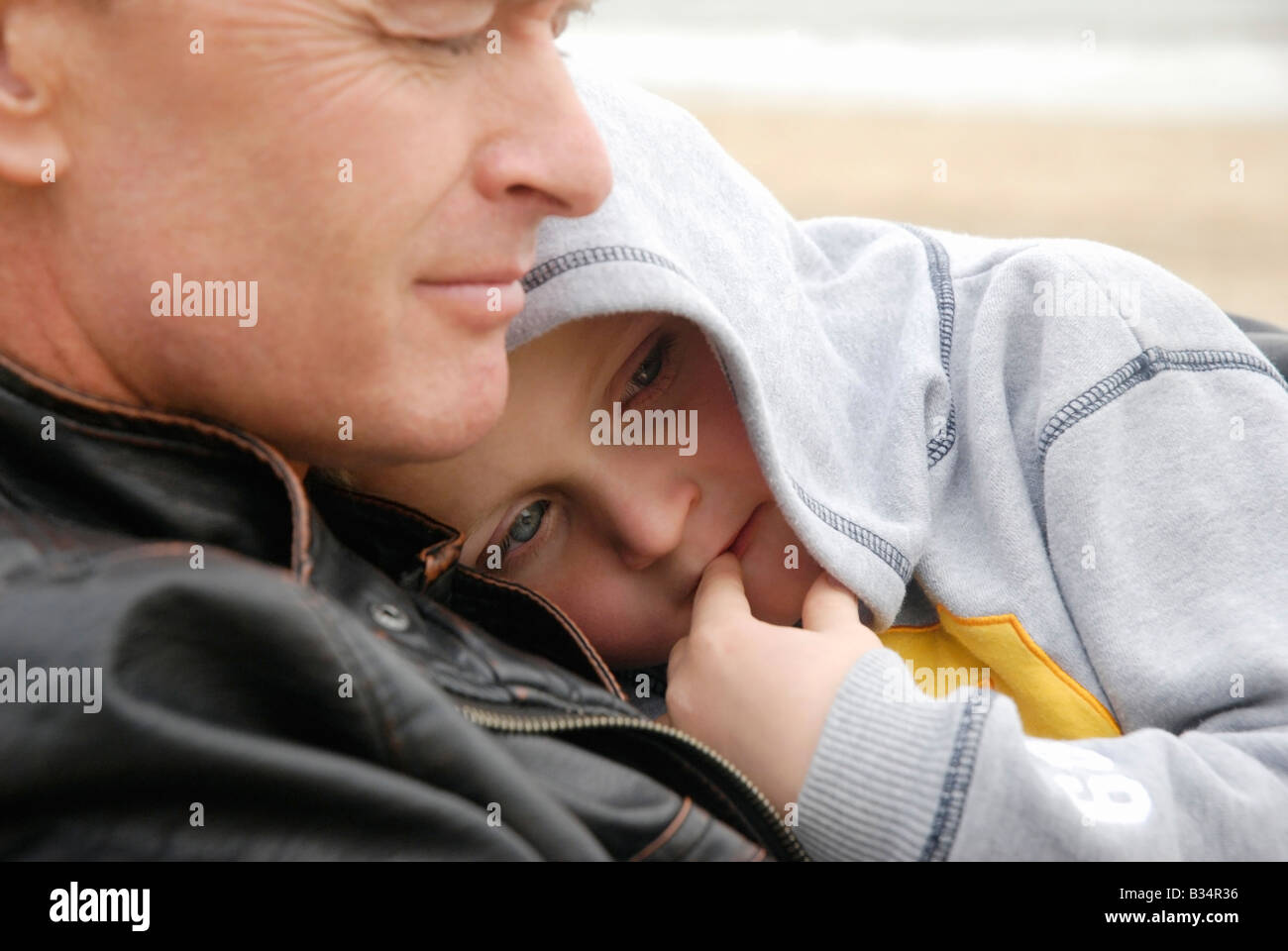 Un jeune garçon de 6 ans de câlins jusqu'à son père durant une journée à la plage. Banque D'Images