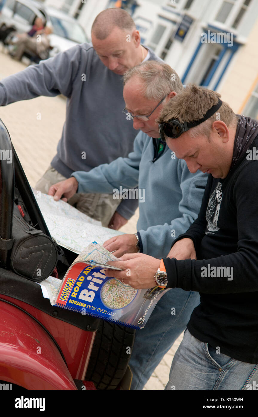 3 Trois hommes se plonger dans des atlas routier Grande-Bretagne la planification de l'itinéraire de leur voiture voyage home - N'utilisez pas sat nav Banque D'Images