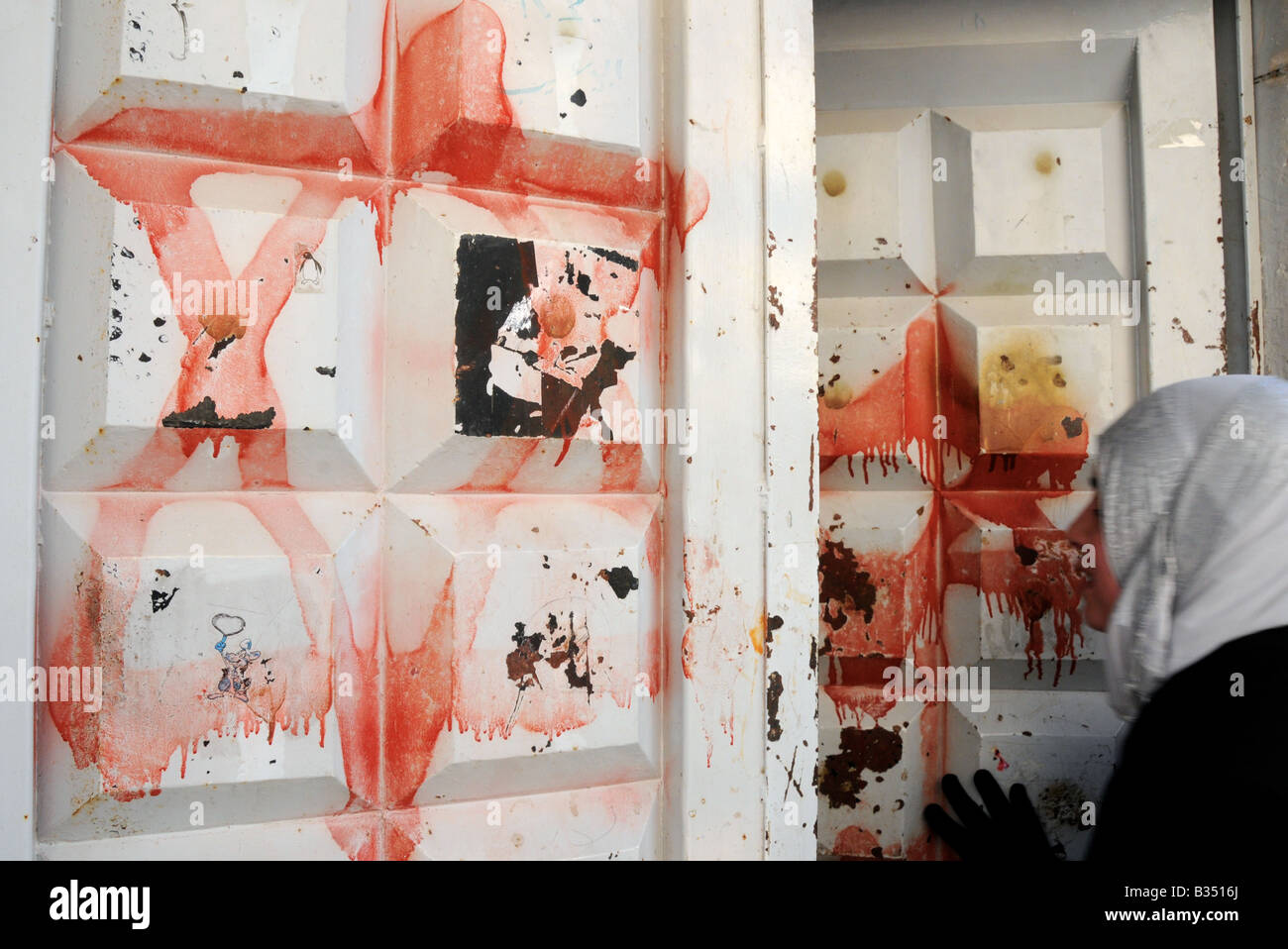 Une fille palestinienne arabe revient à la maison à Hébron, les portes de sa maison peinte avec 'rouge' comme le sang des étoiles de David. Banque D'Images