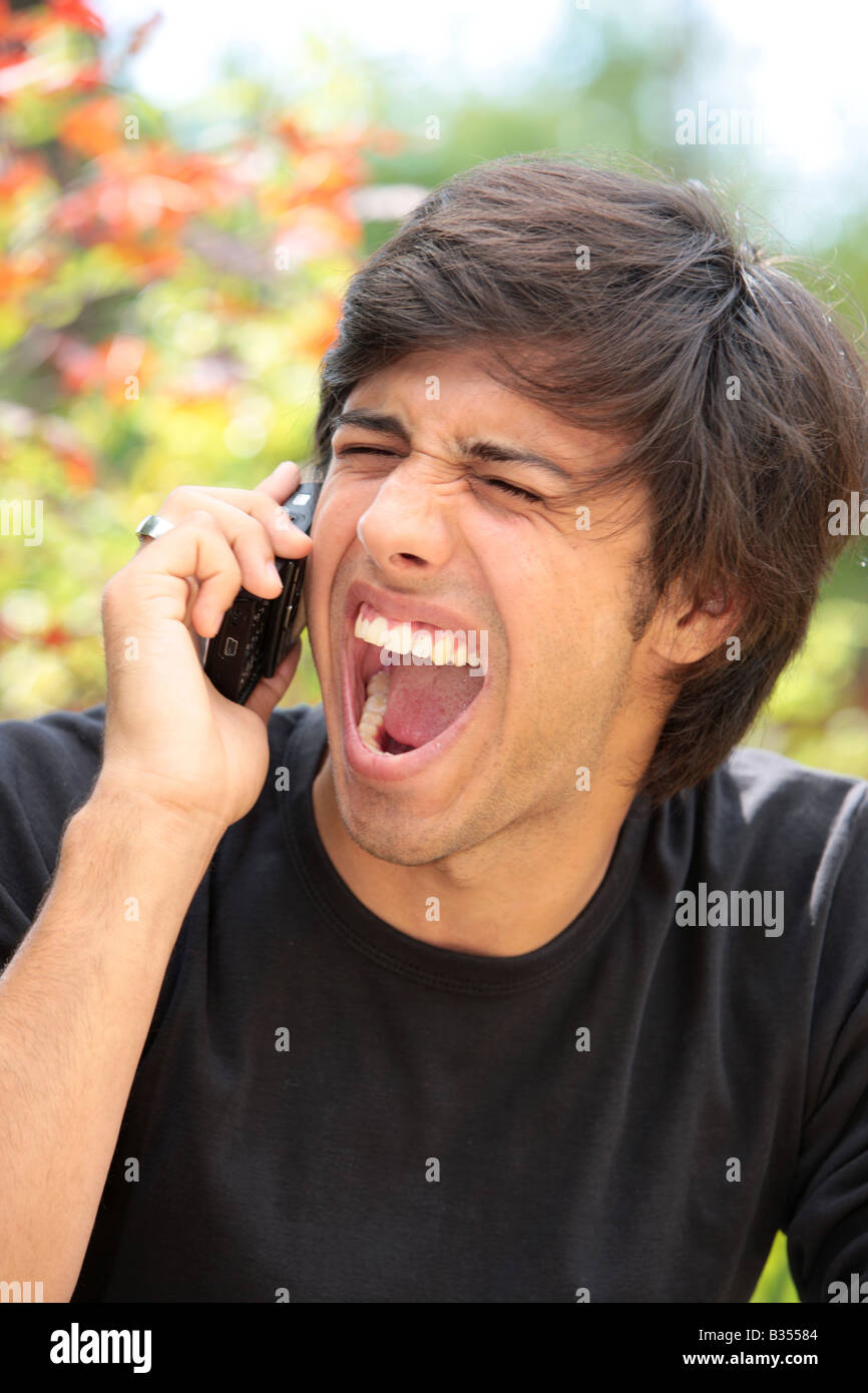 Jeune homme criant sur téléphone mobile Parution Modèle Banque D'Images
