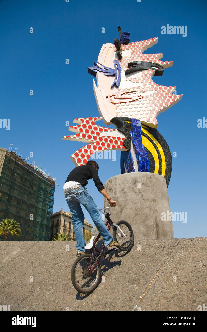 Espagne Barcelone sculpture colorée à Marina Port Vell teenage male circuler à bicyclette jusqu'mur de béton Moll de la Fusta Banque D'Images
