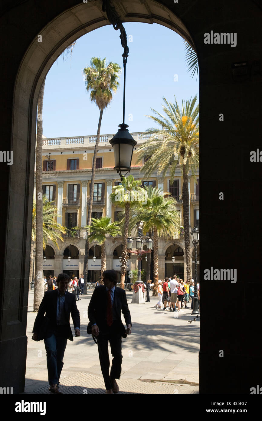 Espagne Barcelone Silhouette de deux personnes marchant à travers arch palmiers et fontaine en plaça Reial en arrière-plan Banque D'Images