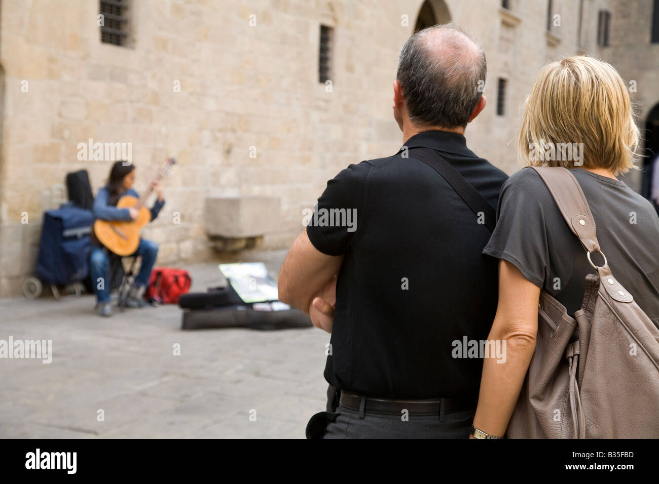 Espagne Barcelone Moyen-âge tourist couple watch femme jouant de la guitare acoustique en Plaça del Rei plaza King s Square Banque D'Images