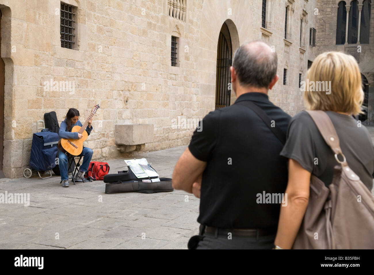 Espagne Barcelone Moyen-âge tourist couple watch femme jouant de la guitare acoustique en Plaça del Rei plaza King s Square Banque D'Images