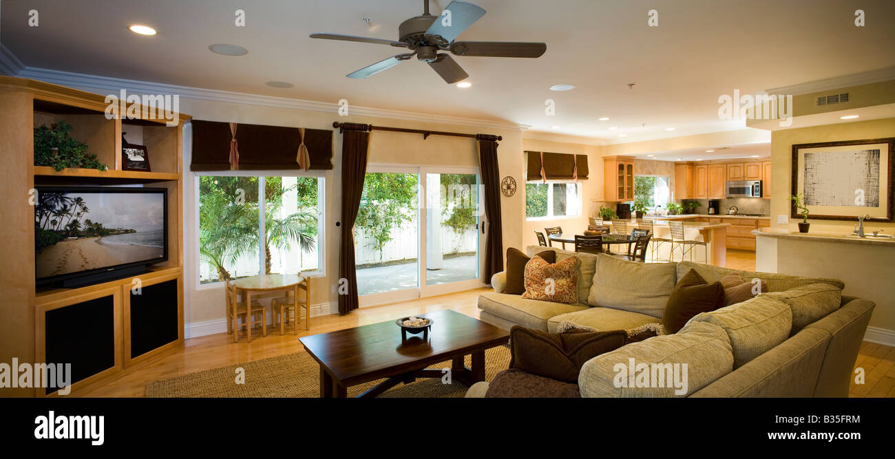 Salon traditionnel jusqu'à l'ouverture de coins et cuisine, d'un ventilateur de plafond, portes coulissantes en verre, et de la télévision. Banque D'Images