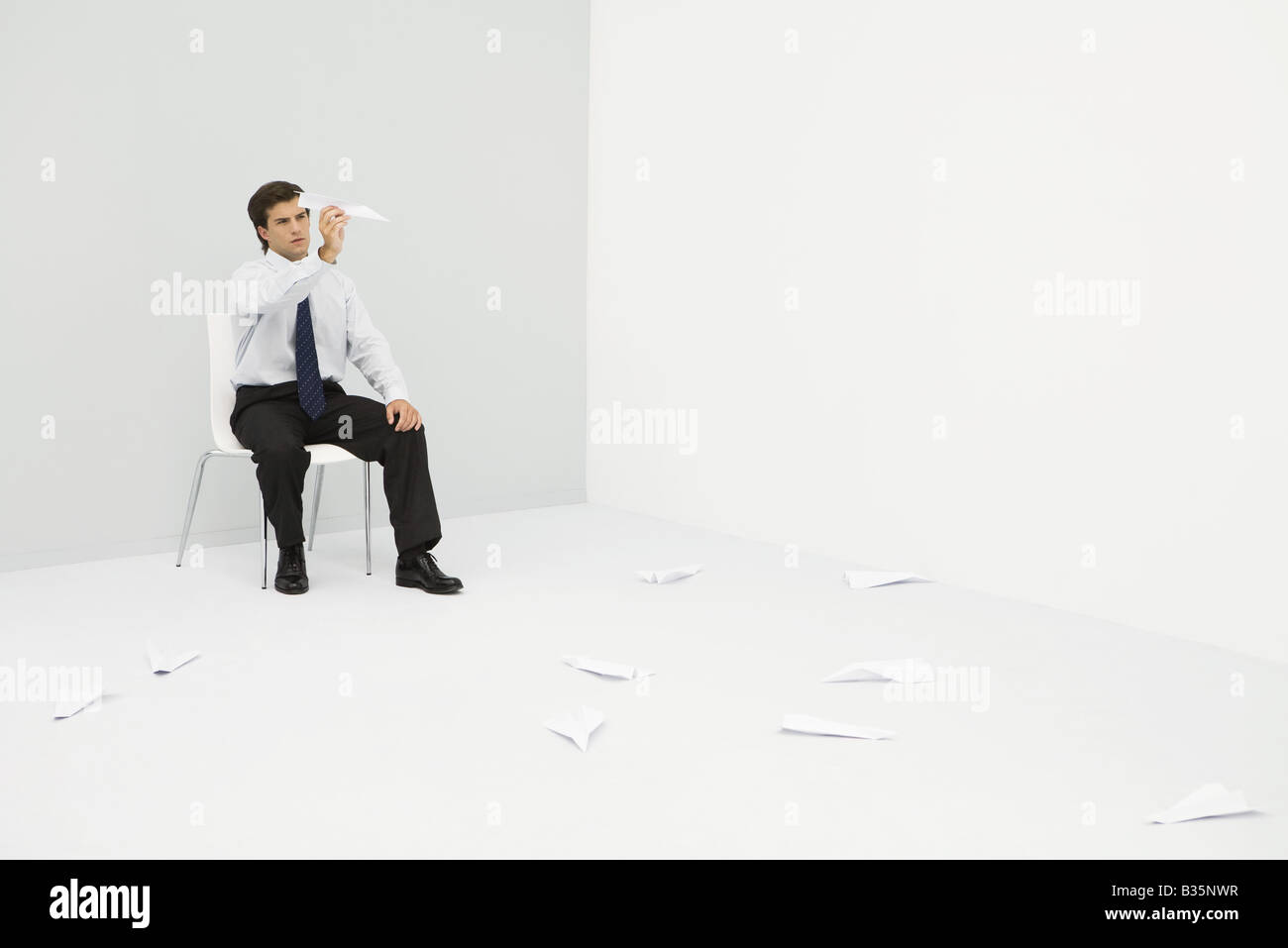 Young man en coin, throwing paper airplanes Banque D'Images