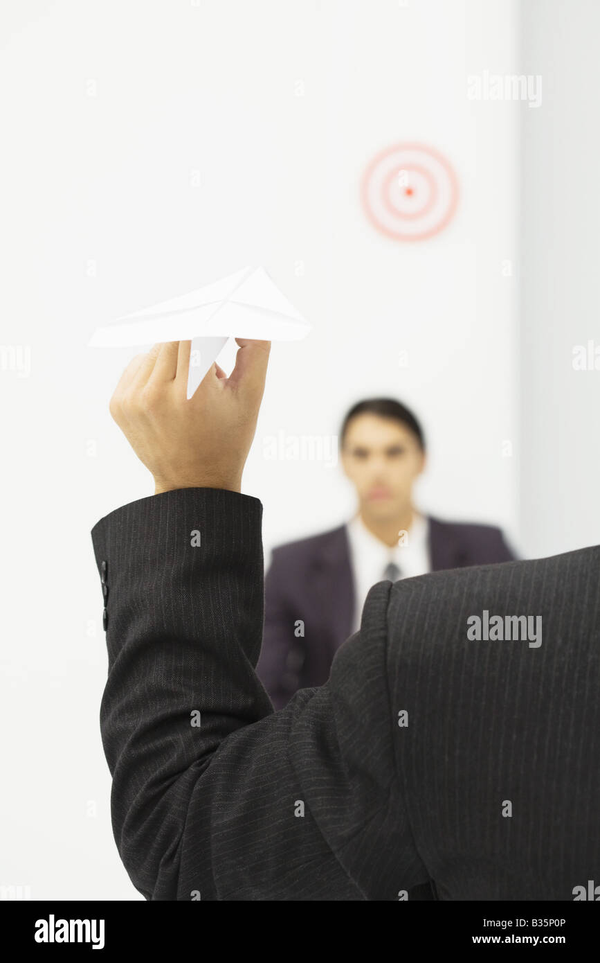 Man holding paper airplane, visant à la cible à la tête du collègue, cropped view Banque D'Images