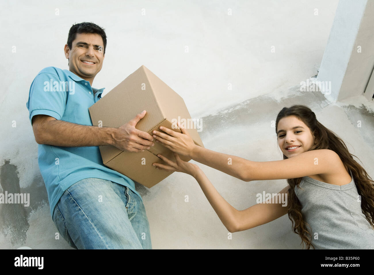 Père et fille déménagement boîte carton ensemble, low angle view Banque D'Images