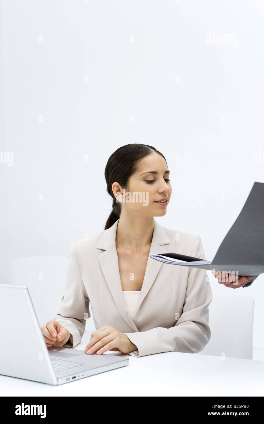 Femme regardant un dossier lieu ouvert pour elle, à l'aide d'un ordinateur portable Banque D'Images