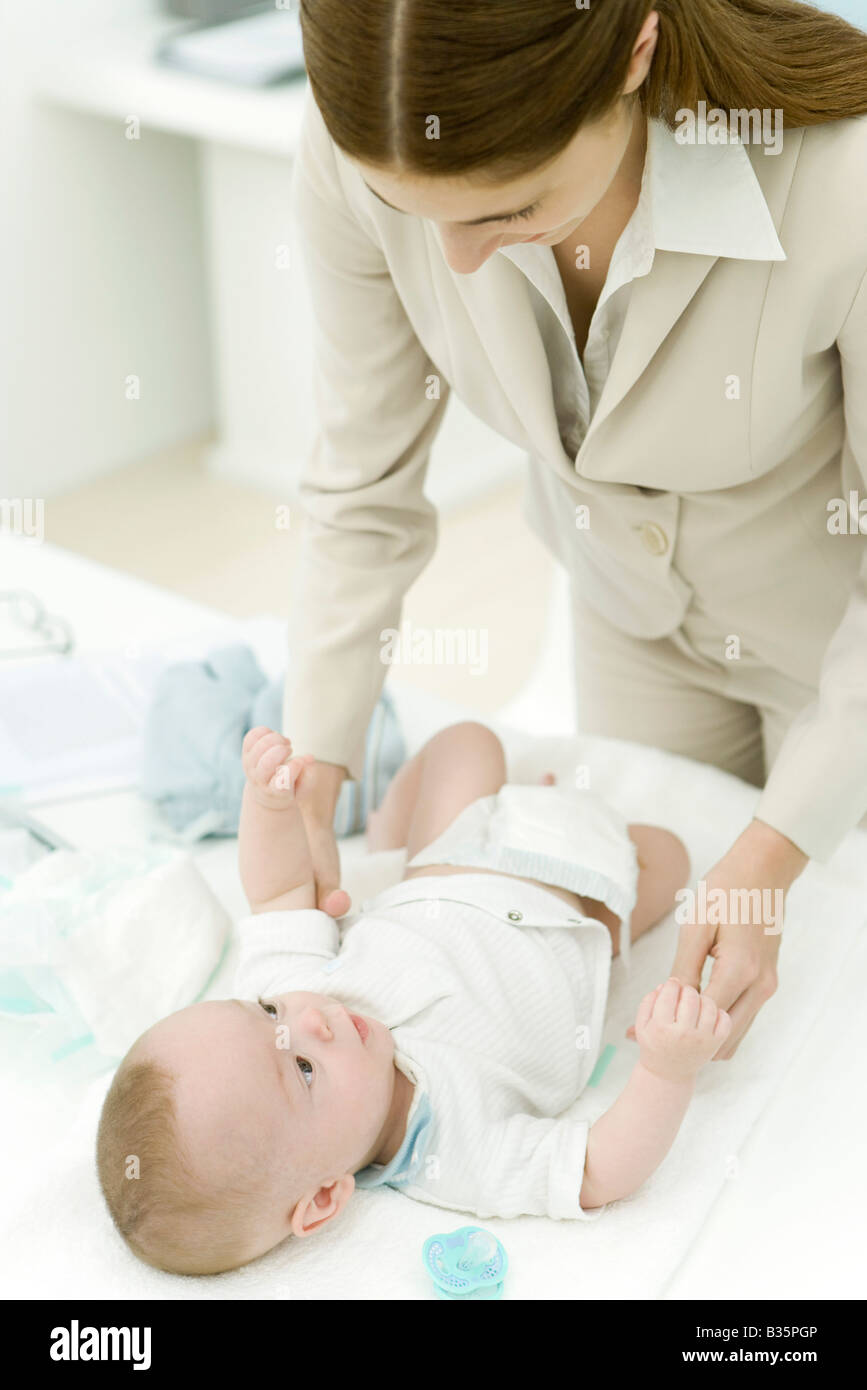 Jeune professionnel mère changer la couche de bébé Banque D'Images