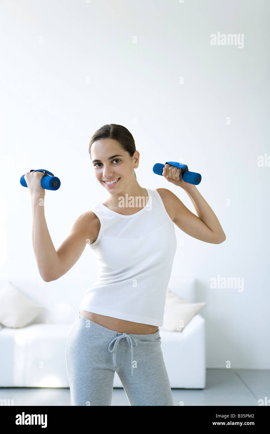 Teen girl lifting dumbbells, smiling at camera Banque D'Images