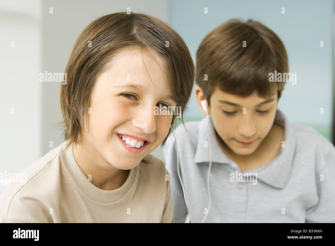 Les garçons, l'un des écouteurs partage smiling at camera, d'autres regardant vers le bas Banque D'Images