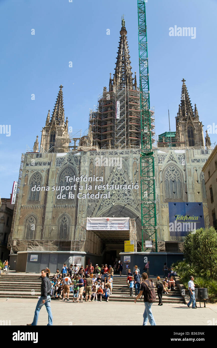 Espagne Barcelone extérieur de cathédrale couverts pour rénovation et restauration foule s'asseoir sur les escaliers de l'église de l'extérieur Banque D'Images