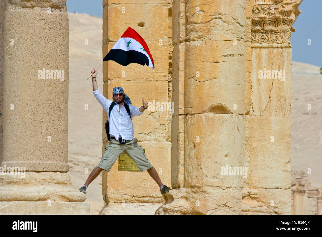 Agiter un drapeau syrien touristiques à des ruines romaines de Palmyre en Syrie Banque D'Images