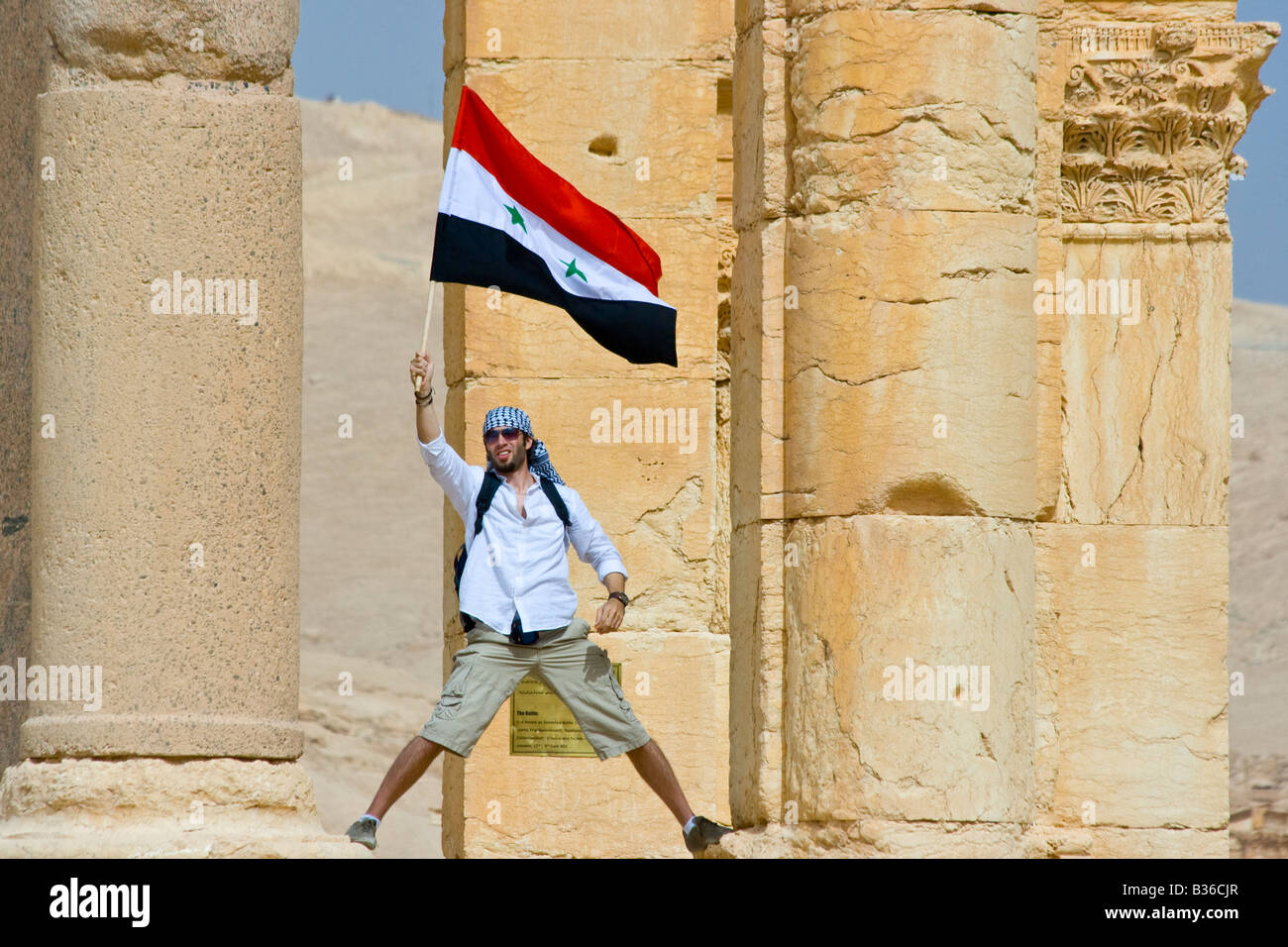Agiter un drapeau syrien touristiques à des ruines romaines de Palmyre en Syrie Banque D'Images