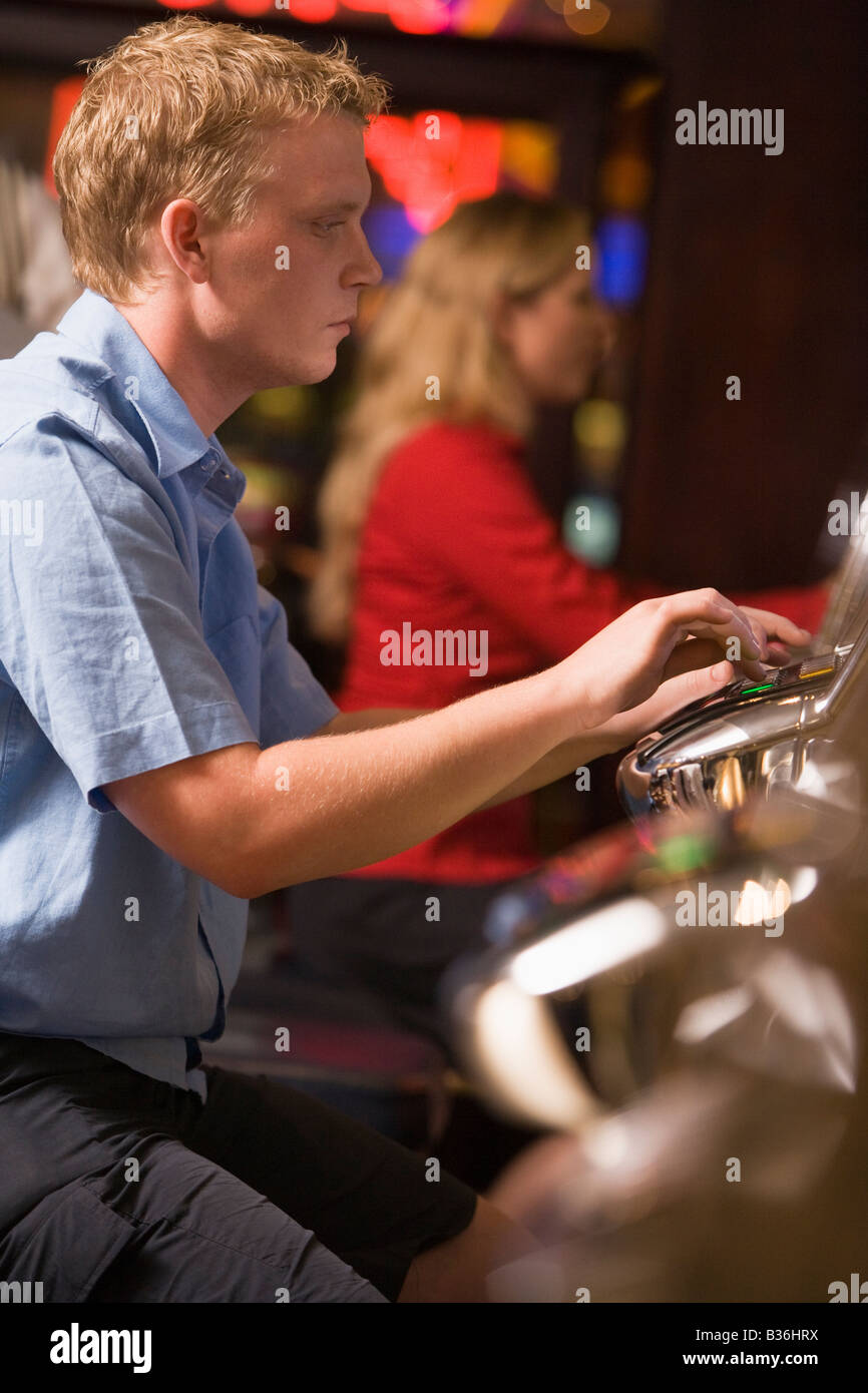 L'homme à la machine à sous casino jouant avec les gens en arrière-plan (selective focus) Banque D'Images