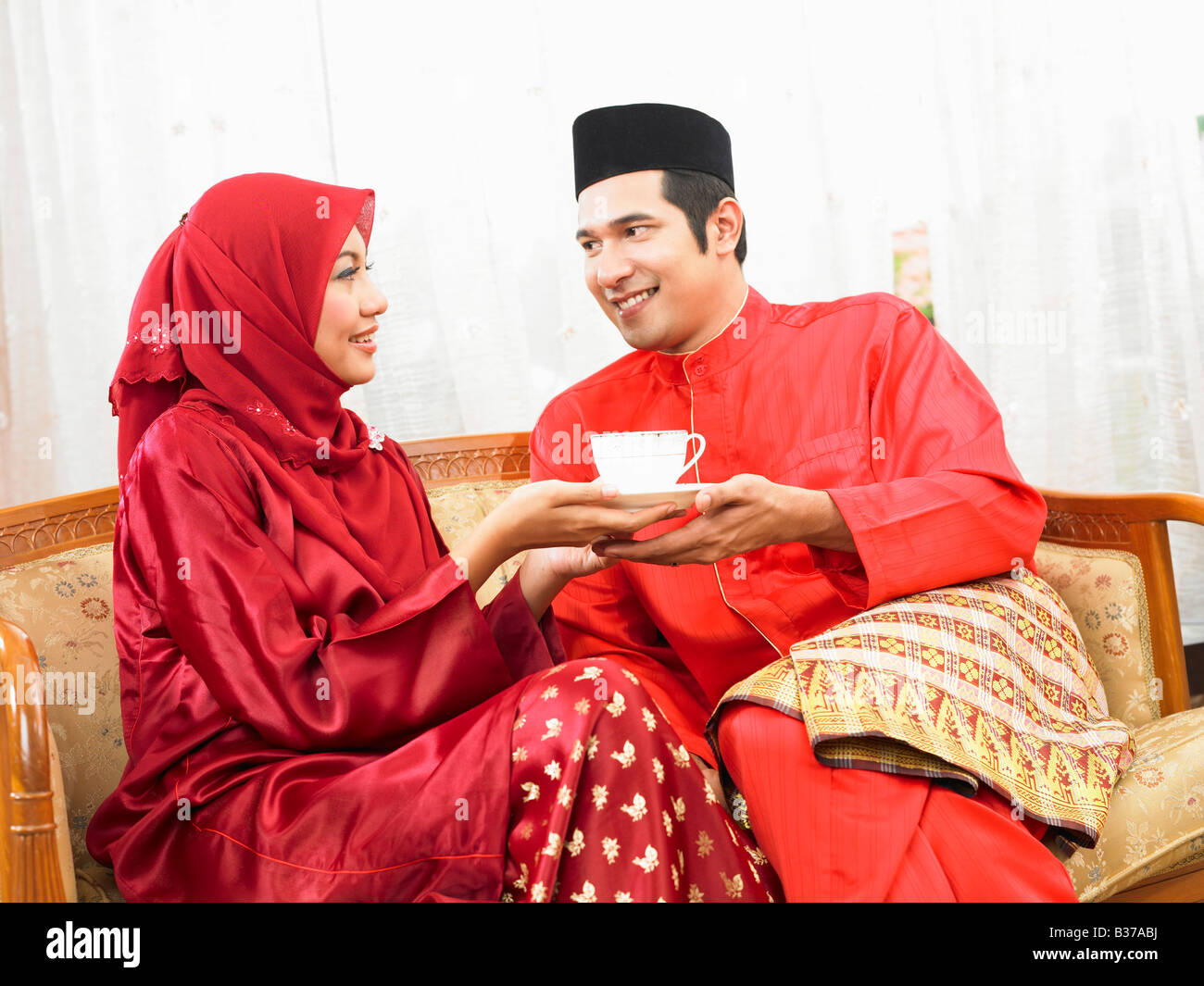 Le malais couple having coffee, sitting on sofa Banque D'Images