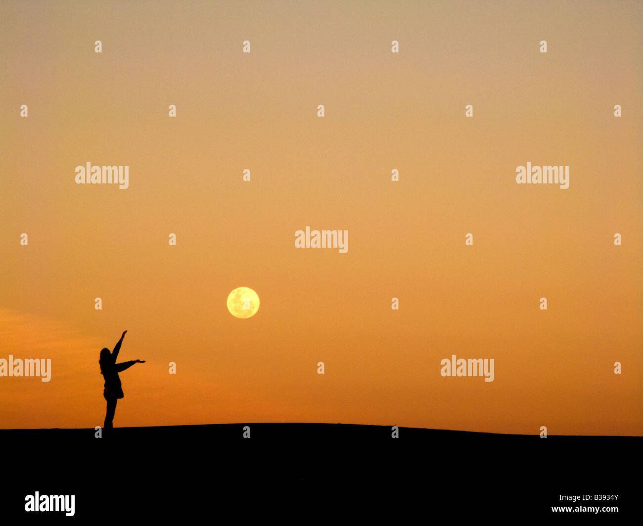 Les enfants marchent sur une dune avec une lune géante Banque D'Images