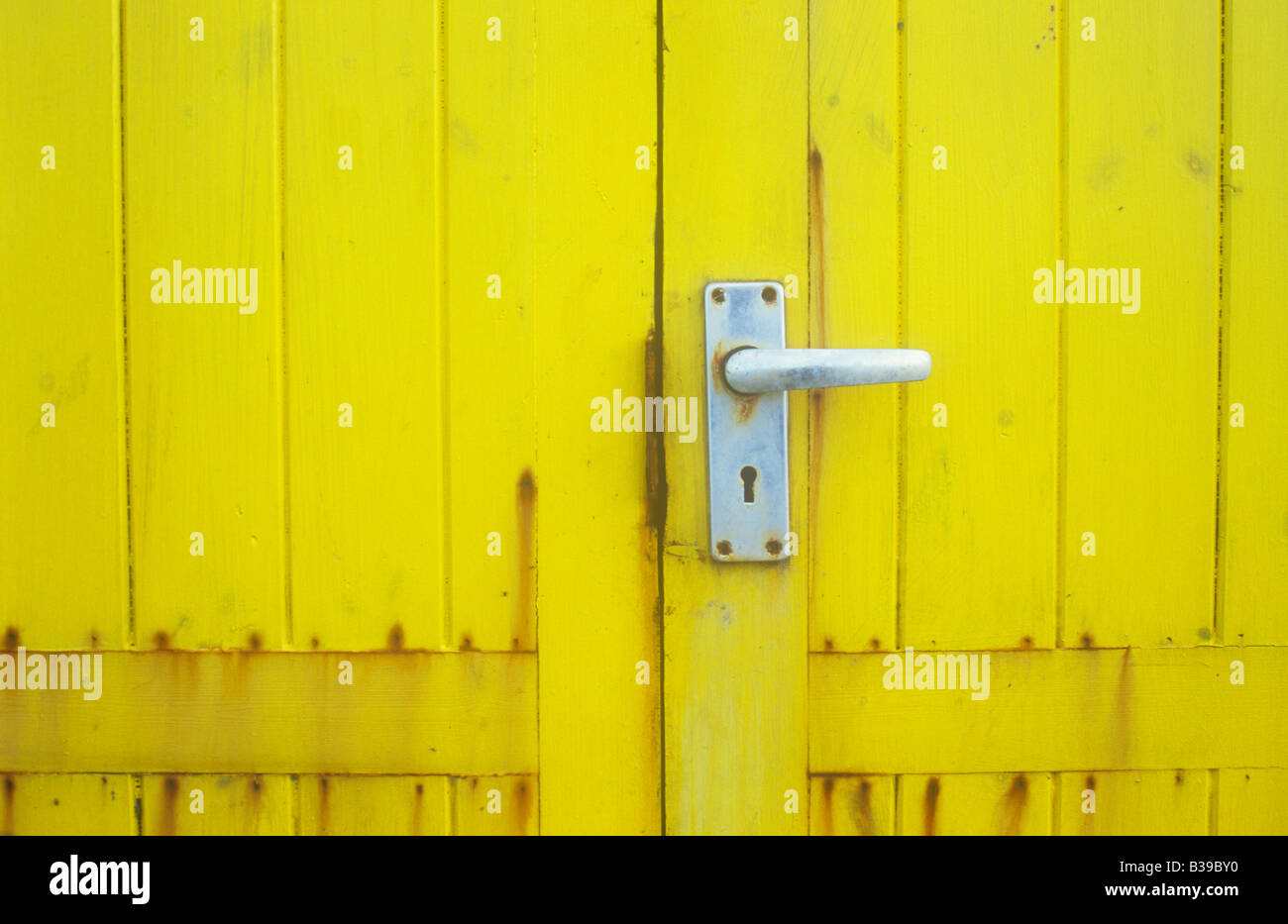 Close up detail de porte en bois teinté jaune sur hut ou hangar ou un  kiosque ou de la cabine en aluminium avec poignée de porte avec les taches  de rouille Photo