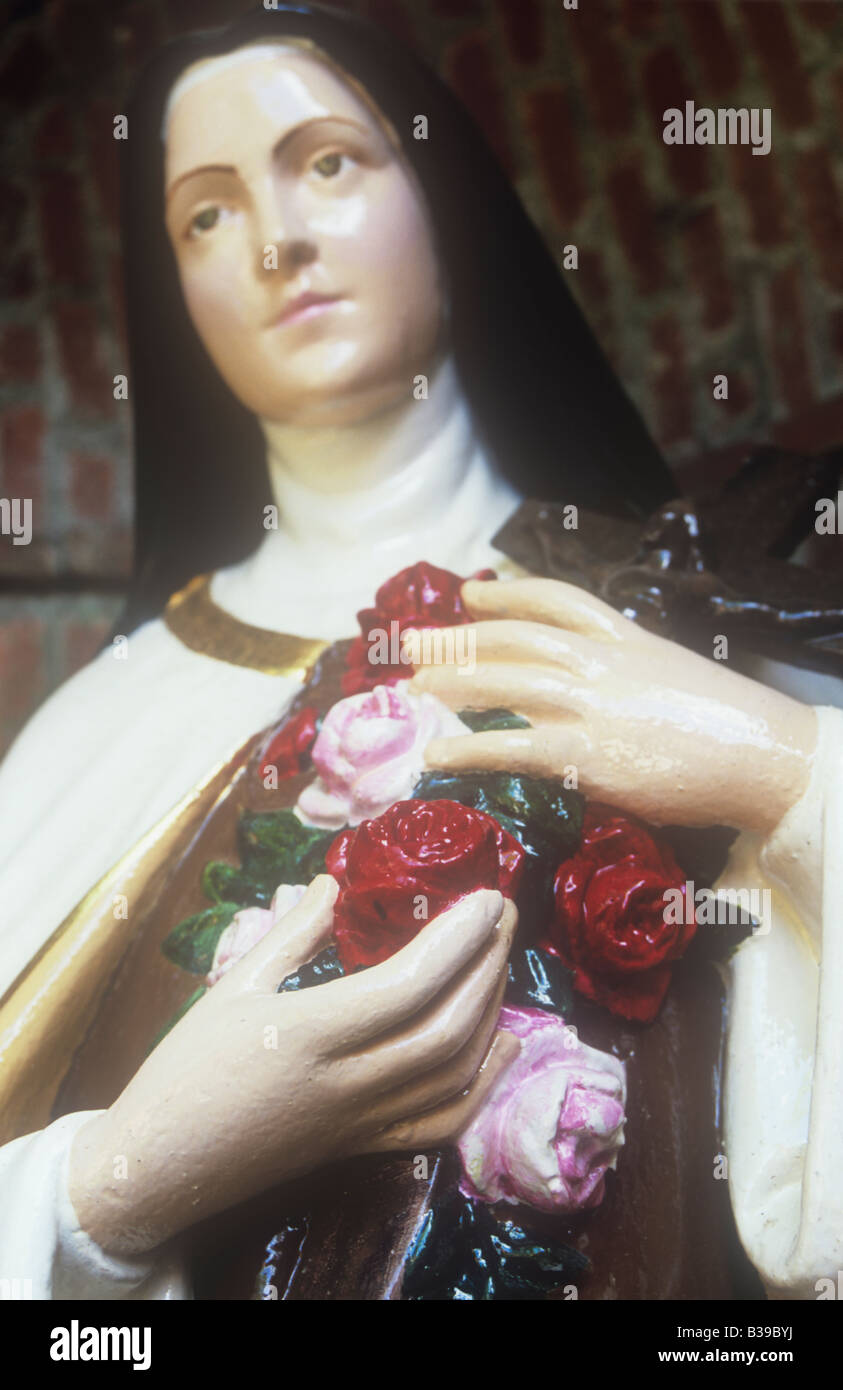 Détail de la sculpture en bois peint de la Vierge Marie sous dôme en brique et la tenue rouge et rose roses et crucifix Banque D'Images