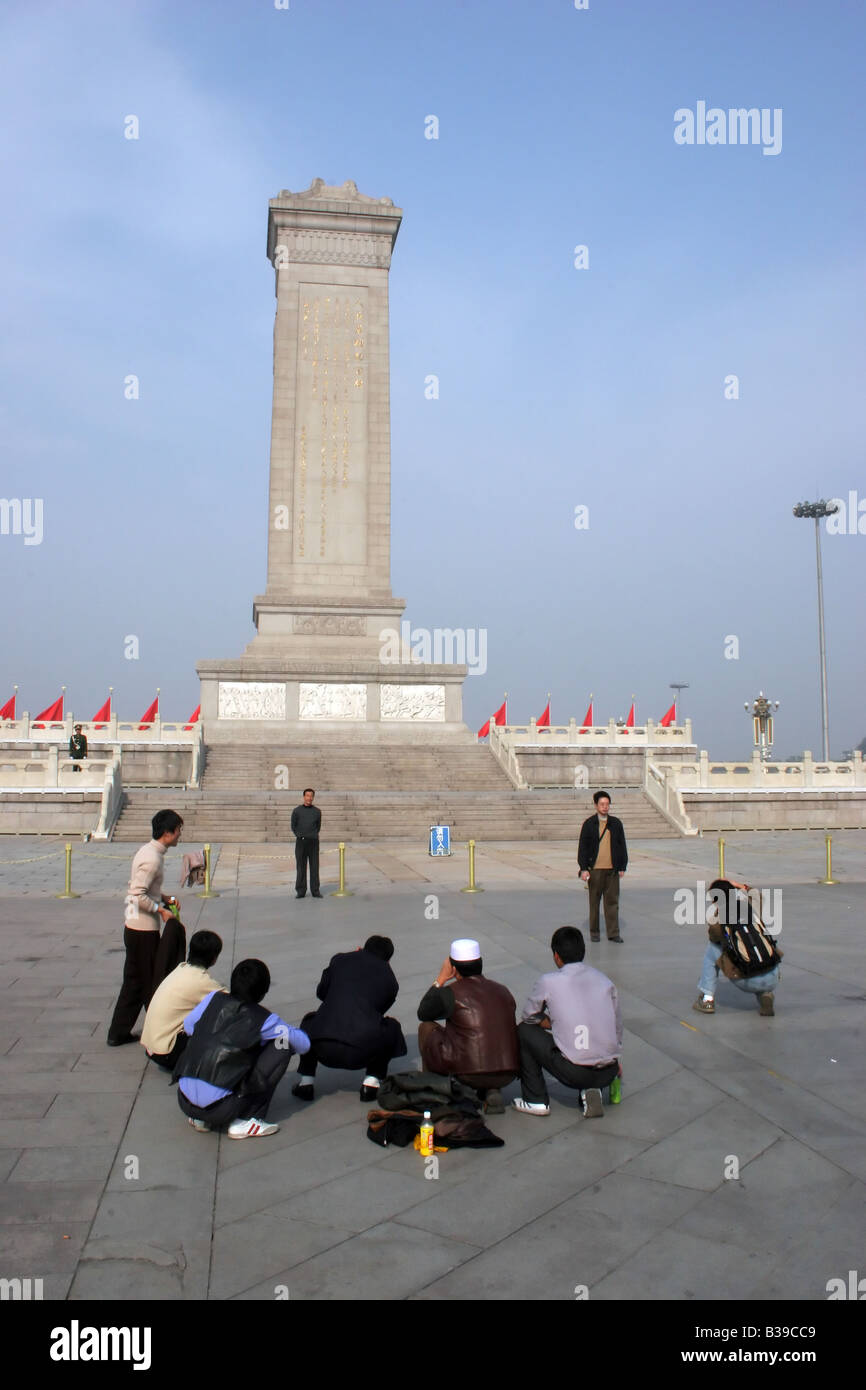 Les touristes se lever et aller de l'avant devant le monument du héros des habitants de la place Tiananmen à Pékin, Chine Banque D'Images