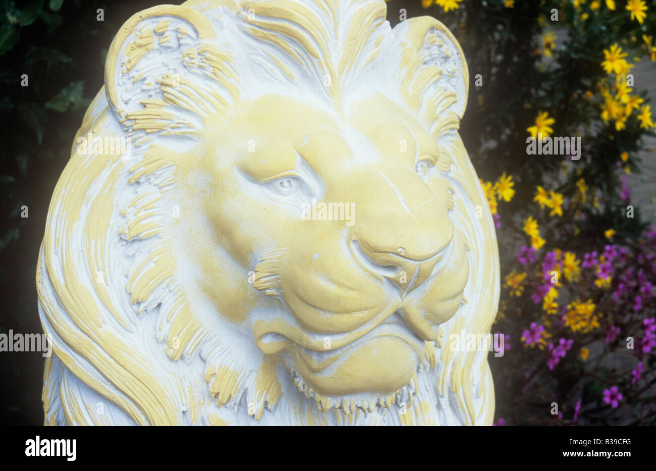 Détail de la tête et la crinière du lion statue de ciment peint en blanc et crème avec des grues de loi et le jardin derrière Heliopsis Banque D'Images Détail de la tête et la crinière du lion statue de ciment peint en blanc et crème avec des grues de loi et le jardin derrière Heliopsis Banque D'Images
