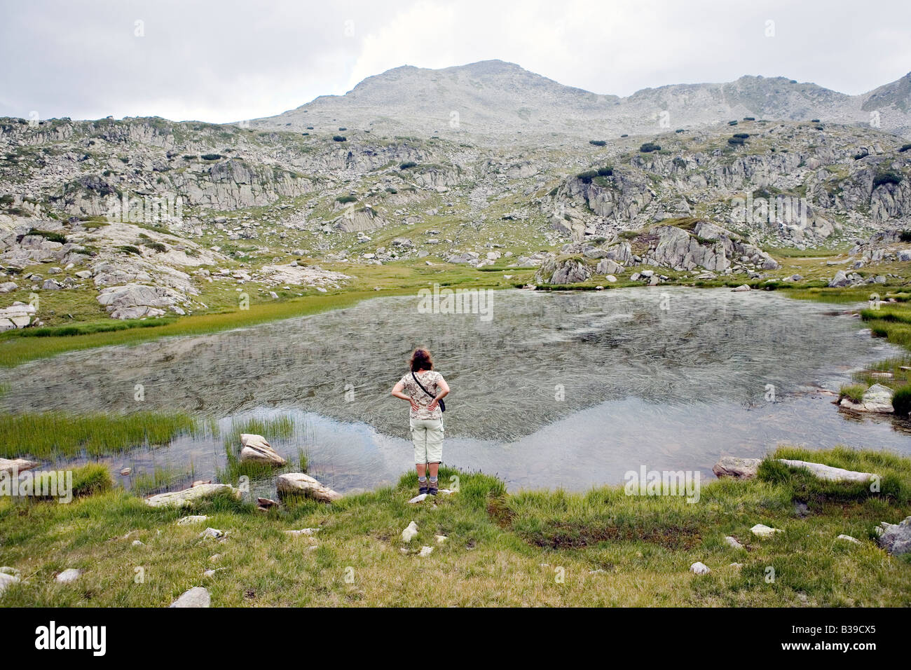 Femme debout à la mire dans le lac Tevno Ezero environs en site du patrimoine mondial Parc national de Pirin Bulgarie Banque D'Images