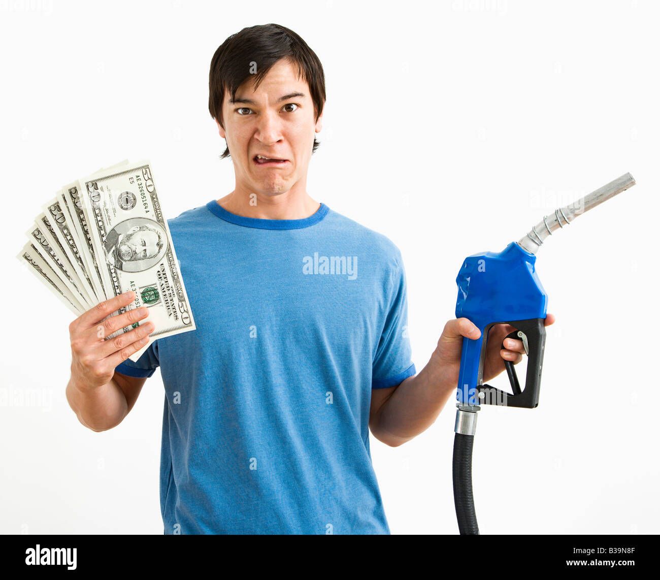 Jeune homme asiatique avec l'expression confuse de la détention de monnaie et du gaz de la buse de la pompe Banque D'Images