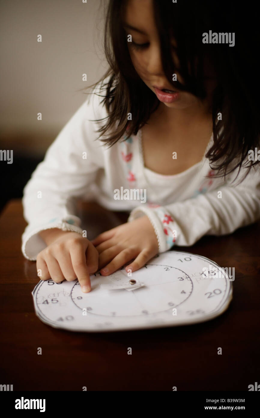 Petite fille de cinq ans indique l'heure avec une horloge papier fait son grand frère à l'école Banque D'Images