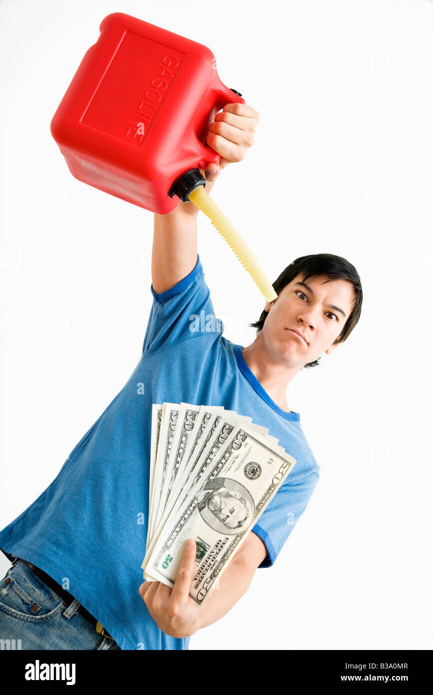 Asian young man holding gaz peut verser de l'argent sur l'essence Banque D'Images