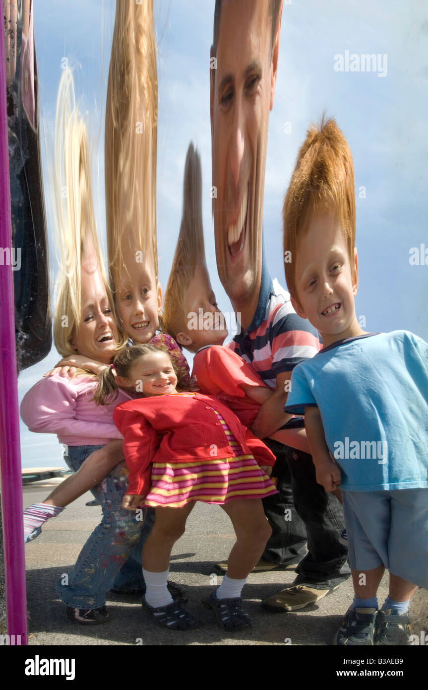 Une jeune famille sur une journée à profiter de la free fun d'un miroir déformant à la mer Banque D'Images