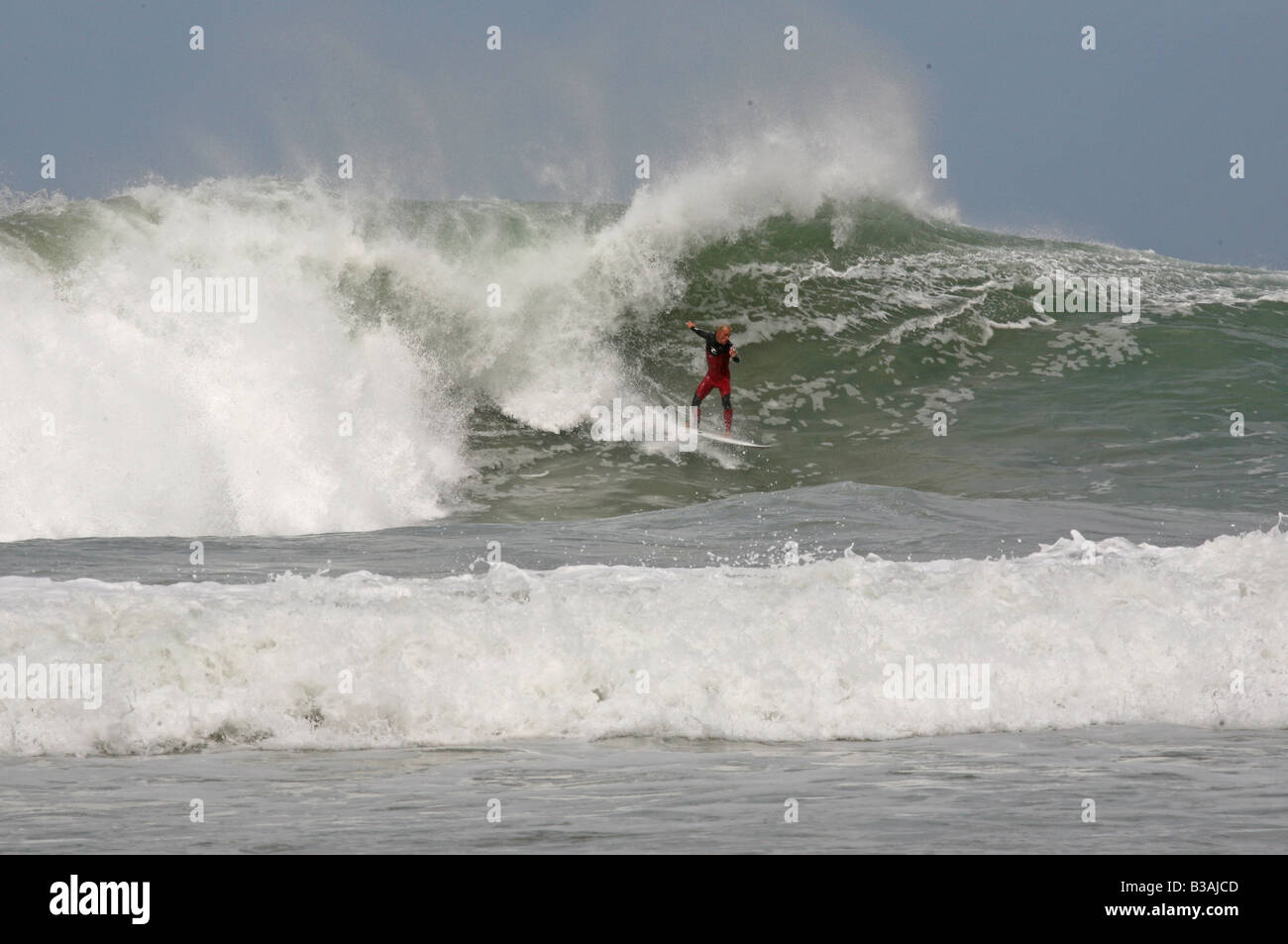 Surfeur sur une grosse vague à Trevaunance Cove, St Agnes, Cornwall, UK Banque D'Images